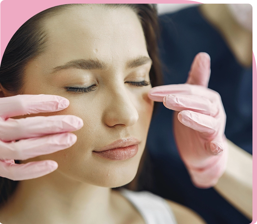 A woman is getting her face painted with pink paint.