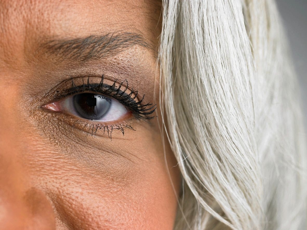 A close up of the eye of a woman with white hair