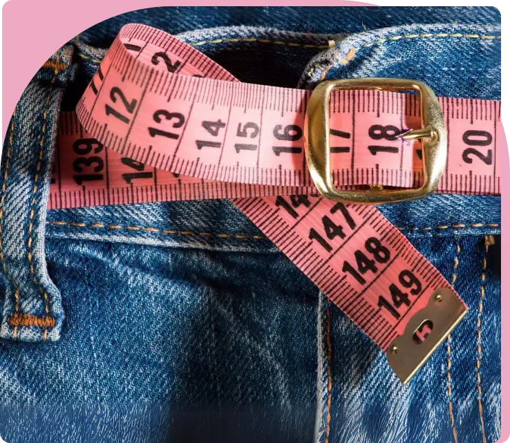 A pink measuring tape is on the waist of someone 's jeans.